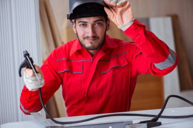 Kaynak tabancası elektrot ve kask takan genç bir tamirci.