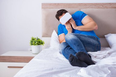 Yatakta sanal gerçeklik başlığı takan genç bir adam.