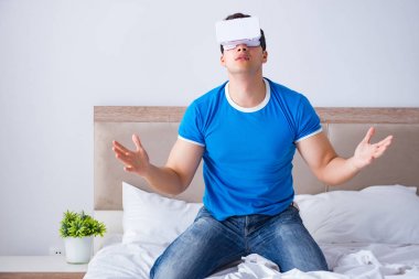 Yatakta sanal gerçeklik başlığı takan genç bir adam.
