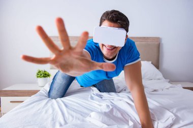 Yatakta sanal gerçeklik başlığı takan genç bir adam.