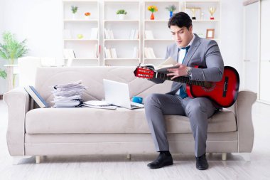 Evde gitar çalan bir iş adamı.