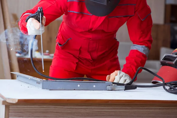 Kaynak tabancası elektrot ve kask takan genç bir tamirci.