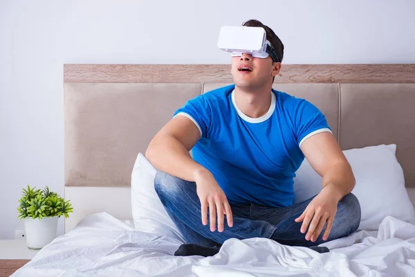 Yatakta sanal gerçeklik başlığı takan genç bir adam.
