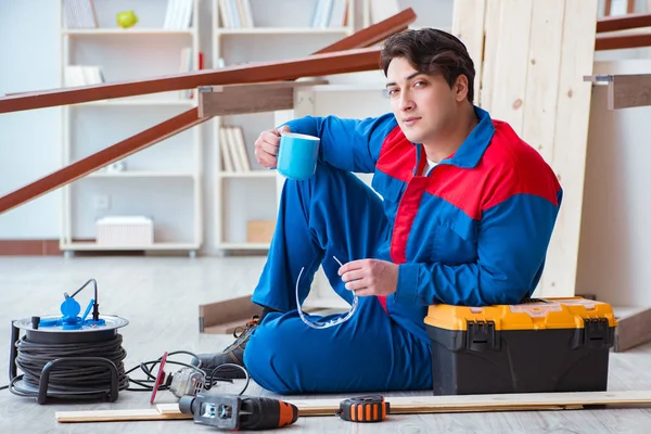 Genç marangoz ahşap kalaslarla çalışmaya ara veriyor.