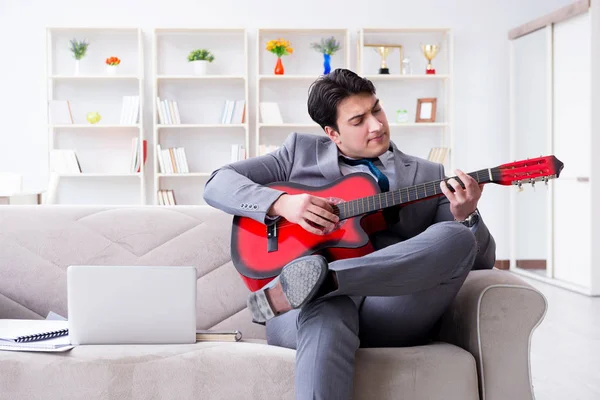 Evde gitar çalan bir iş adamı.