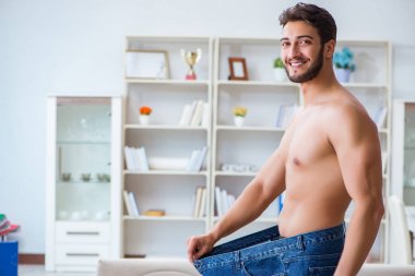 Kilo verme konseptinde büyük beden pantolon giyen bir adam.