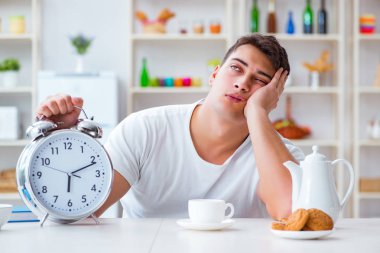 Çalar saati olan bir adam kahvaltıda uyuyakalıyor.