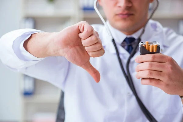 Médico masculino en concepto anti-tabaquismo con paquete de cigarrillos —  Fotos de Stock