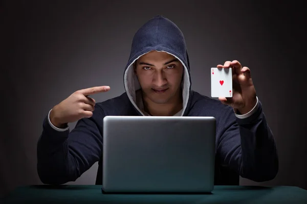 Joven con una sudadera con capucha sentado frente a una computadora portátil — Foto de Stock