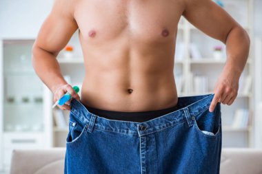 Kilo verme konseptinde büyük beden pantolon giyen bir adam.