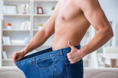 Kilo verme konseptinde büyük beden pantolon giyen bir adam.