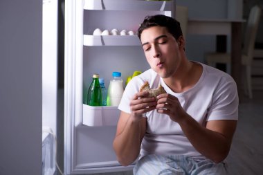 Buzdolabındaki adam gece yemek yiyor.