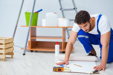 Tamirci, duvar kağıdıyla evde tadilat yapıyor.