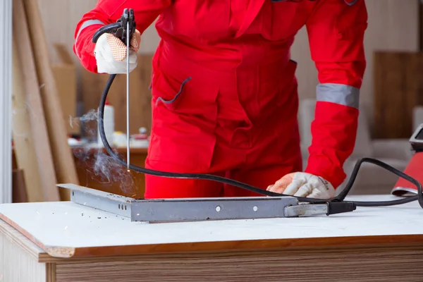 Kaynak tabancası elektrot ve kask takan genç bir tamirci.