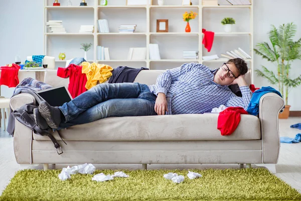 Genç adam dağınık bir odada çalışıyor.