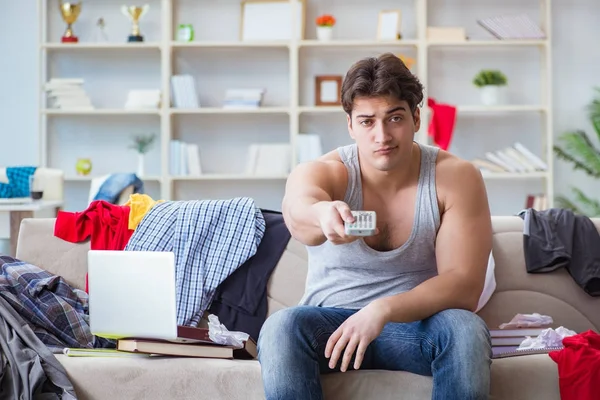 Genç adam dağınık bir odada çalışıyor.