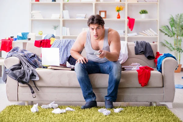 Genç adam dağınık bir odada çalışıyor.