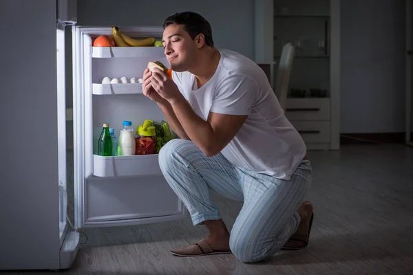 Человек в холодильнике ест ночью — стоковое фото