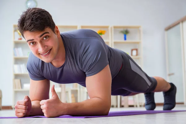 Giovane uomo che esercita a casa in sport e stile di vita sano con — Foto Stock