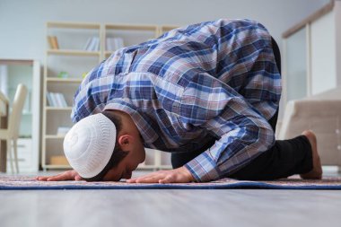 Genç Müslüman adam evde dua ediyor.