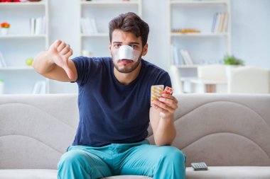 Genç adam estetik cerrahi burnundan sonra evde iyileşiyor.