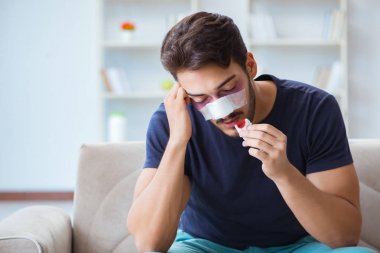 Genç adam estetik cerrahi burnundan sonra evde iyileşiyor.