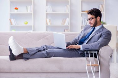 Koltuk değneği ve kırık bacağı olan bir iş adamı.