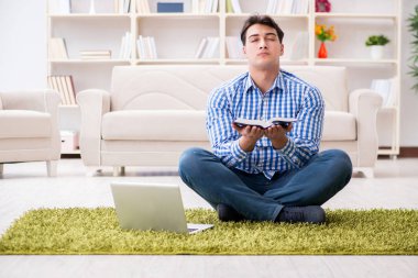Genç yakışıklı adam evde yerde oturuyor.