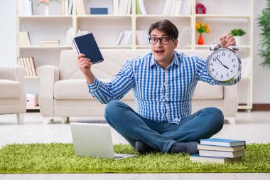 Genç yakışıklı adam evde yerde oturuyor.