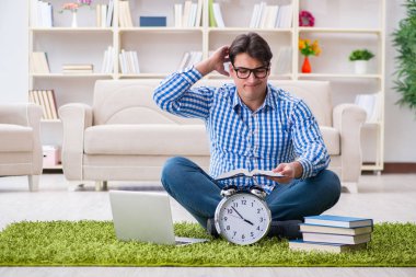 Genç yakışıklı adam evde yerde oturuyor.