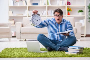 Genç yakışıklı adam evde yerde oturuyor.