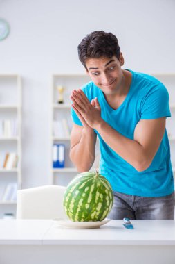 Evde karpuz yiyen bir adam.