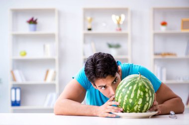 Evde karpuz yiyen bir adam.