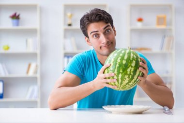 Evde karpuz yiyen bir adam.