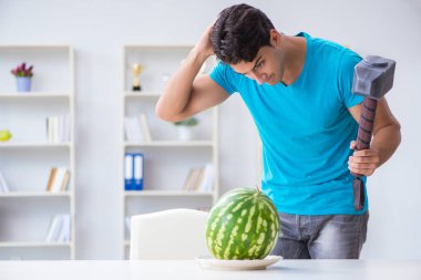 Evde karpuz yiyen bir adam.