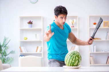 Evde karpuz yiyen bir adam.