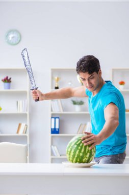 Evde karpuz yiyen bir adam.