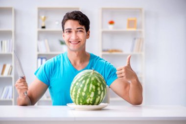 Evde karpuz yiyen bir adam.