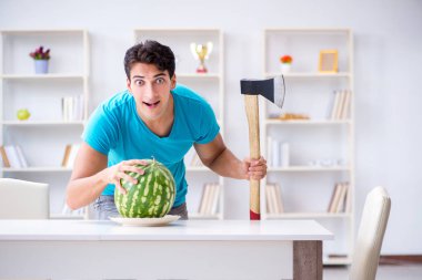 Evde karpuz yiyen bir adam.