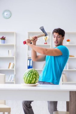 Evde karpuz yiyen bir adam.