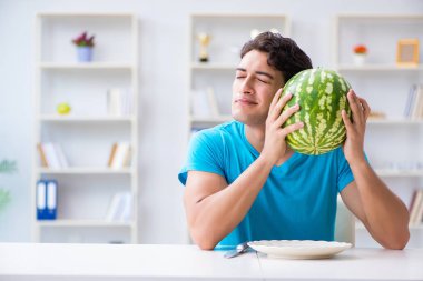 Evde karpuz yiyen bir adam.