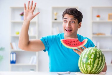 Evde karpuz yiyen bir adam.
