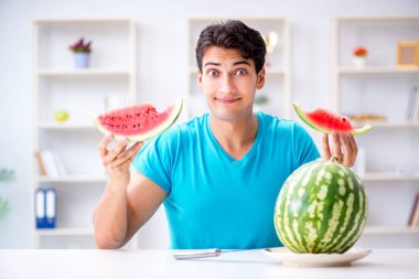 Evde karpuz yiyen bir adam.