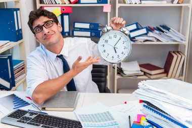 Ofiste kitap ve kağıtlarla çalışan bir işadamı.