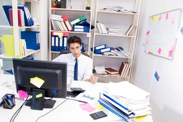 Businessman working in the office with piles of books and papers — Stock Photo, Image