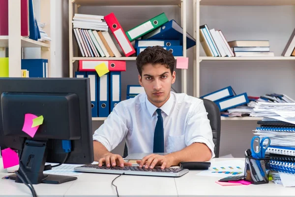 Ofiste kitap ve kağıtlarla çalışan bir işadamı.