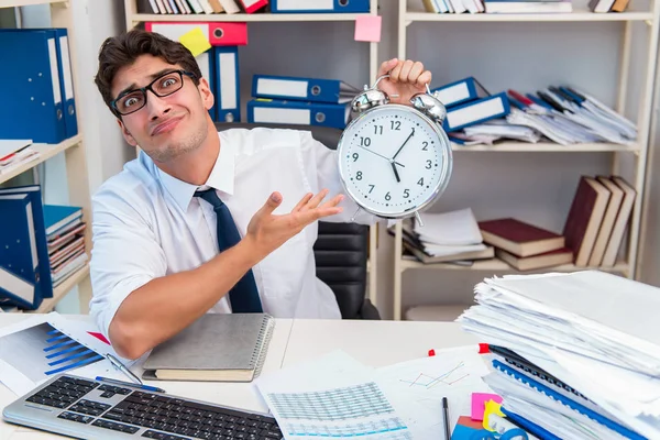 Zakenman werkzaam in het kantoor met stapels boeken en papieren — Stockfoto