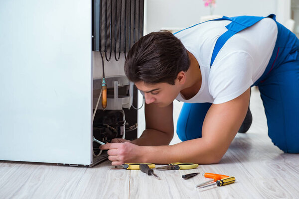 Repairman contractor repairing fridge in DIY concept