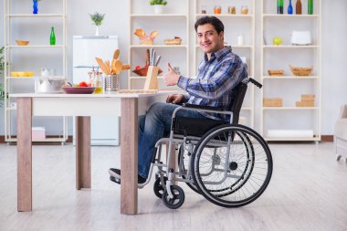 Engelli genç koca mutfakta çalışıyor.