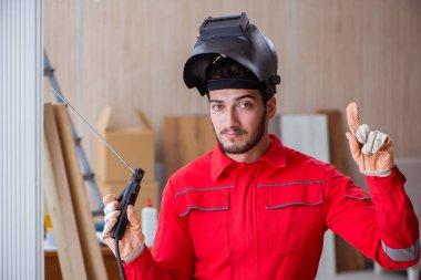 Kaynak tabancası elektrot ve kask takan genç bir tamirci.